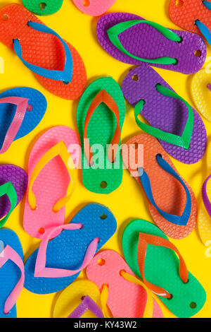 Collezione di coloratissimi estate flip flop sandali su un brillante sfondo giallo Foto Stock