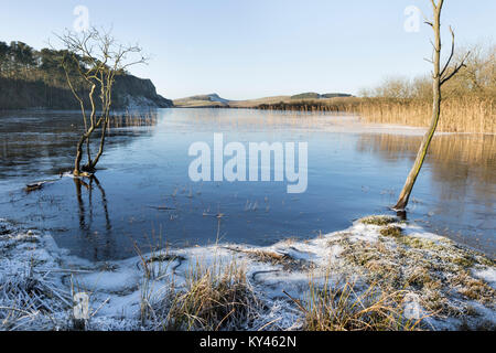 Il Vallo di Adriano: falesia di Lough, congelato nella morsa di inverno, su una bella giornata di sole. La vista guardando ad ovest verso l'acciaio Rigg Winshield e falesie. Foto Stock