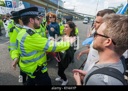 La polizia spingere indietro i manifestanti che stanno bloccando l'ingresso al centro ExCeL a lato della strada per consentire ad un camion per andare al Salone DSEi Arms Fair. Foto Stock