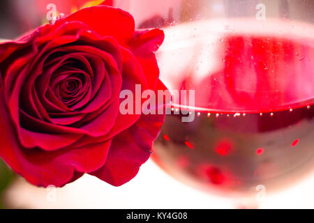 Una rosa rossa e vino rosso Foto Stock