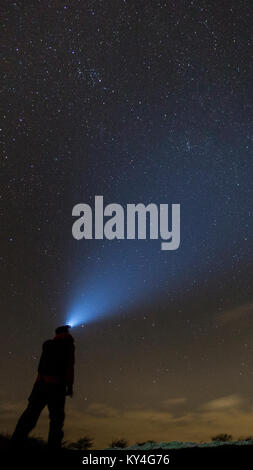 Ditchling Beacon, Sussex, Regno Unito. Un lone persona che indossa una luminosa torcia da testa a Guarda in chiaro, cielo stellato su Ditchling Beacon. Foto Stock