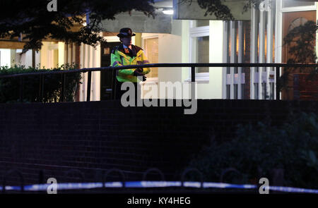 Una poliziotta sta di guardia da uno degli ingressi di appartamenti in Ollgar vicino al suo incrocio con la vecchia strada in quercia, Shepherd's Bush dopo un fatal stabbing. Foto Stock