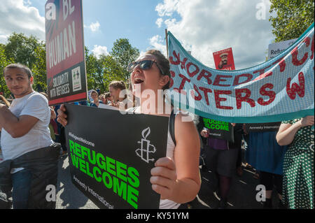 "I profughi Benvenuti' è stato il chiaro messaggio su un Amnesty International poster portati di fronte alla Shoreditch sorelle W. I. banner. Foto Stock