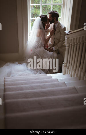 Sposa e lo sposo seduta sul davanzale della finestra e baciare Foto Stock