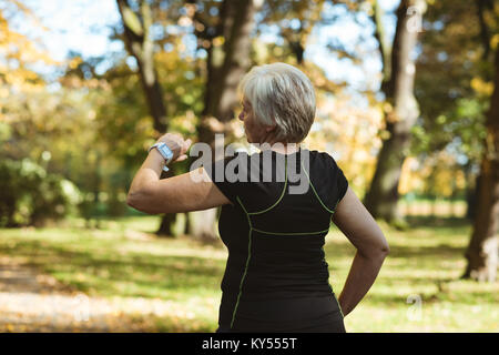 Senior donna utilizzando un orologio intelligente in un parco Foto Stock