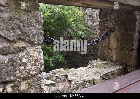 Vista la scappatoia catena protetta nel castello. In primo piano è una panca in legno. Foto Stock