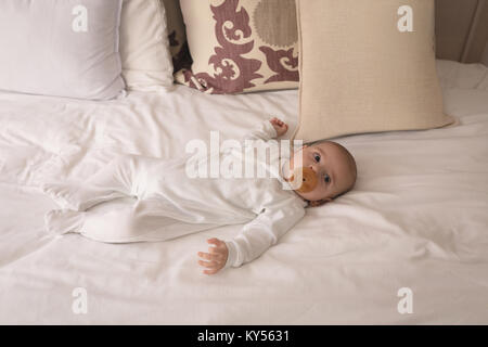 Carino piccolo bambino con il succhietto nella bocca di dormire sul letto Foto Stock