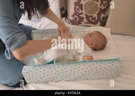 Carino piccolo bambino di vestirsi da sua madre sul letto in camera da letto Foto Stock