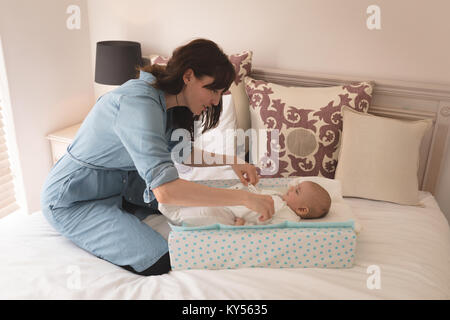 Carino piccolo bambino di vestirsi da sua madre sul letto in camera da letto Foto Stock