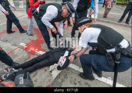 Alcuni manifestanti che rifiutano di muoversi sono sollevati dalla polizia e trascinato verso il marciapiede come si cancella la strada dopo il mock funebre per le vittime del commercio di armi da Londra i lavoratori cattolici. Non ci erano arresti. Foto Stock