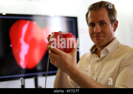 Uomo con modello di plastica di un cuore umano Foto Stock