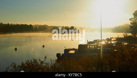 Misty soleggiato vista sul lago e le barche all'alba, Ljustero, contea di Stoccolma, Svezia, in Scandinavia. Foto Stock