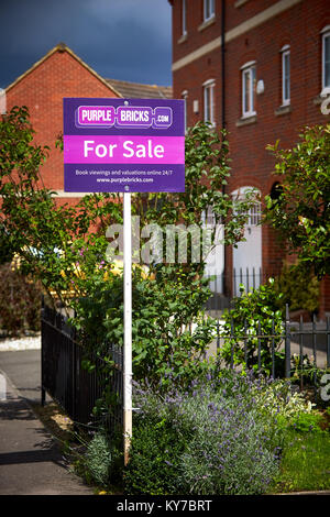 Un viola mattoni agenti immobiliari in vendita segno esterno di una casa su di un moderno complesso residenziale in Aylesbury, Buckinghamshire Foto Stock