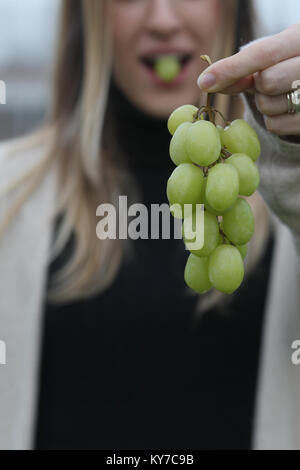 In Spagna è una tradizione di mangiare dodici uve per Capodanno. Una giovane donna mangia l'uva per la Vigilia di Capodanno in Spagna. Foto Stock