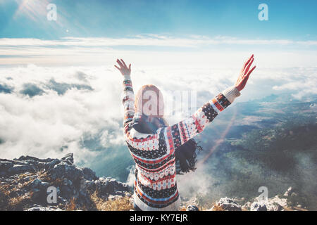 Felice ragazza sul vertice di montagna le mani sollevate oltre le nuvole stile di vita viaggio concetto di successo avventura vacanze attive outdoor Foto Stock