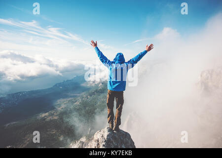 L'uomo viandante sul vertice di montagna gode di vista aerea le mani sollevate oltre le nuvole stile di vita viaggio concetto di successo avventura vacanze attive outdoor happ Foto Stock