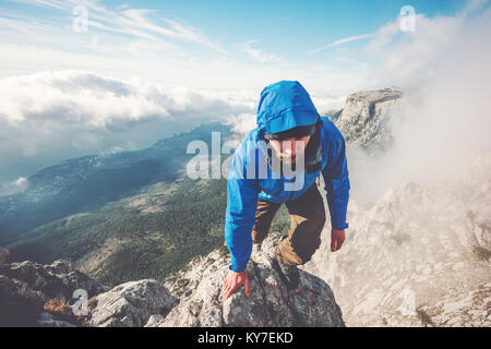 L'uomo Traveler arrampicata sul vertice di montagna sopra le nuvole stile di vita viaggio concetto di successo avventura vacanze attive outdoor sport estremi Foto Stock