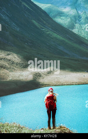 Ragazza Backpacker permanente sulla scogliera sopra il lago di montagna in stile di vita viaggio adventure concept vacanze estive all'aperto esplorando la natura selvaggia Foto Stock