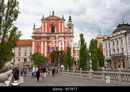 Barocca chiesa francescana dell Annunciazione, conosciuta anche come la chiesa di rosa, Lubiana, Slovenia , con parte del famoso tripple ponte Ljublj Foto Stock