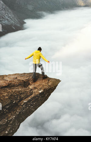 L'uomo turistico Trolltunga sulla scogliera rocciosa montagne di bordo Stile di vita viaggio avventura concetto emotivo wanderlust vacanze in Norvegia all'aperto al di sopra delle nuvole Foto Stock