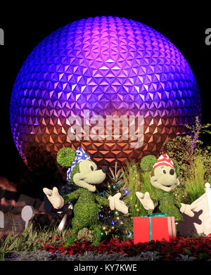 Disney's Epcot Center sfera illuminata di notte durante la stagione di vacanze con Topolino e Minnie e Plutone caratteri erba sculture sul foregr Foto Stock