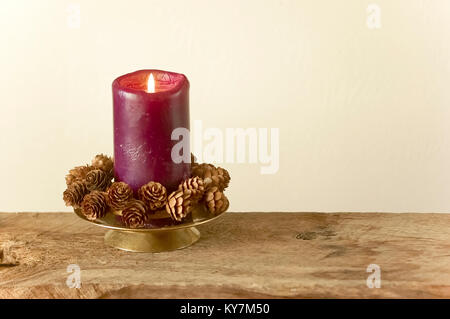 Vacanza viola candela decorazione semplice con pigne nelle quali il legno rustico per Natale o per l Avvento Foto Stock