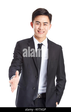 Studio shot di un giovane imprenditore Asiatico raggiungendo fuori per una stretta di mano, guardando la telecamera sorridendo, isolato su sfondo bianco. Foto Stock