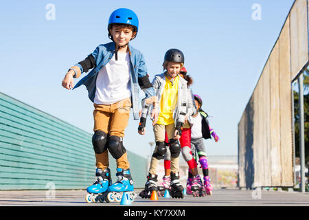 Ritratto di preteen boy, felice inline skater, imparare a evitare i coni in corso di slalom all'aperto Foto Stock