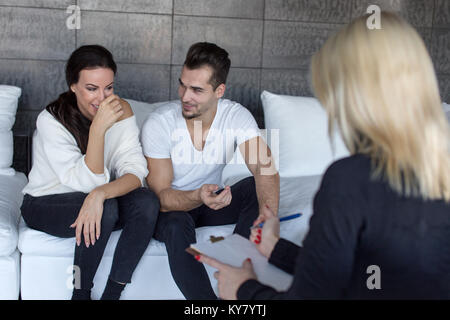 Coppia sorridente e scherzando sulla terapia a psichiatra in ambienti interni Foto Stock