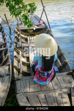 Una donna vietnamita in abito tradizionale seduta sulla barca di legno. Foto Stock