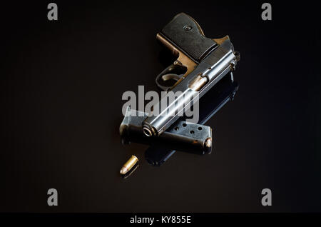 Pistola, caricabatteria e bullet nero su sfondo riflettente Foto Stock