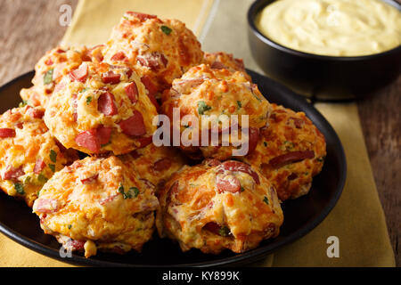 Pane appena sfornato deliziose palline di salsiccia con il formaggio cheddar e verdi su una piastra di close-up su una tavola orizzontale. Foto Stock
