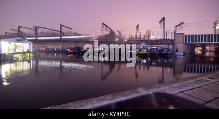 Un treno si avvicina London St Pancras stazione ferroviaria su un viadotto attraverso il Regent's Canal su una suggestiva notte di nebbia, con una lunga esposizione motion Foto Stock