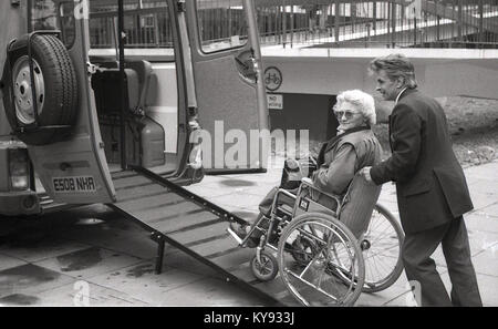 Anni ottanta, storico, signora anziana in carrozzina che viene spinto fino a rampa in un minivan come parte del servizio di communicare per i disabili e gli anziani fornita da Easington consiglio della contea di Durham, Inghilterra. Foto Stock