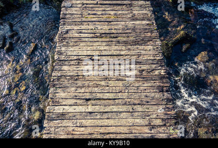 Immagine concettuale di un malsicuro passerella di legno su un ruscello o fiume o torrente in Scozia Foto Stock