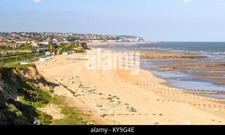 Un treno corre a fianco della spiaggia di St Leonards in East Sussex, Inghilterra, con la città di Hastings dietro. Foto Stock