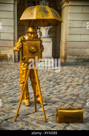 Lviv, Ucraina - 23 Marzo 2014: l'uomo - un attore che pongono in abiti colorati e un volto ai cittadini del quartiere antico della città di Lviv, Ucraina. Foto Stock