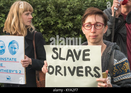 Una donna al Regno voci del mondo al di fuori di protesta Sotheby's auto asta trattiene un poster 'Slave driver'. Foto Stock