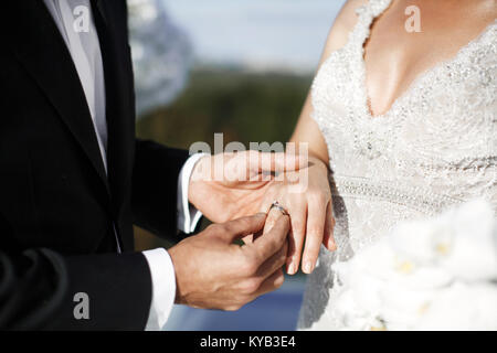 Lo sposo indossa anello sulla sposa del dito. W Foto Stock