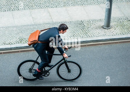 Giovane uomo che indossa business suit mentre in sella ad una bicicletta di utilità Foto Stock