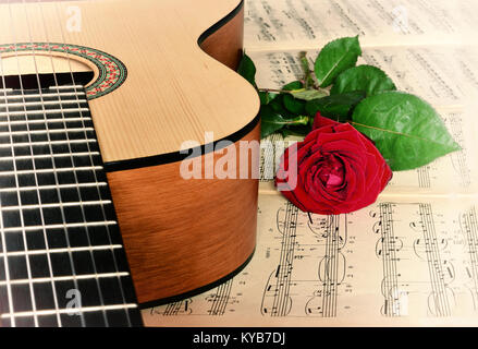 Rose rosse, chitarra acustica sul foglio di musica come sfondo. Foto Stock