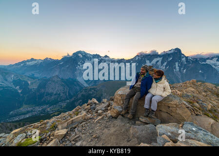Paio di persone che guardano il tramonto sul Mont Blanc picco di montagna (4810 m). Valle d'Aosta, italiano avventure estive e destinazione di viaggio sul Foto Stock
