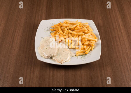 Costolette di maiale con salsa bianca e patate fritte su sfondo bianco Foto Stock