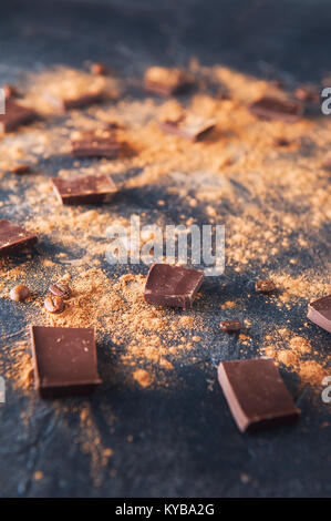 Barra di cioccolato pezzi, la polvere di cacao e caffè in grani sulla pietra scuro dello sfondo. Lo sfondo con il cioccolato. Fette di cioccolato. Sweet Food concept foto Foto Stock