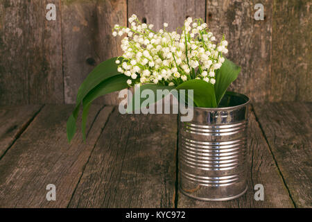 Bouquet di mughetti in un vaso di metallo su un sfondo di legno. tonica foto Foto Stock