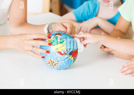 Multiculturale mani per bambini su un globo Foto Stock