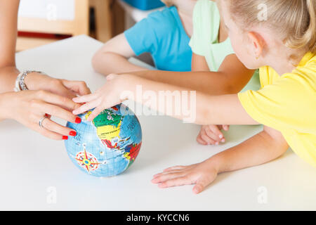 Multiculturale mani per bambini su un globo Foto Stock