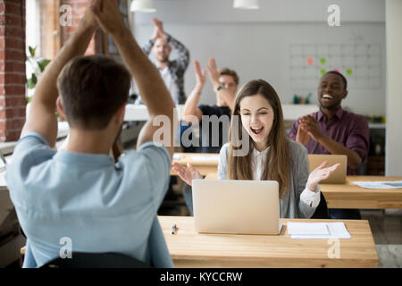 Excited donna guardando lo schermo del notebook sorpreso dal buon online news win conseguimento, team aziendale ai colleghi congratulandomi con un collega con il business Foto Stock