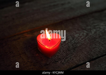 A forma di cuore la masterizzazione di candela su sfondo di legno, il giorno di San Valentino concetto Foto Stock