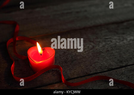 A forma di cuore la masterizzazione di candela su sfondo di legno, il giorno di San Valentino concetto Foto Stock